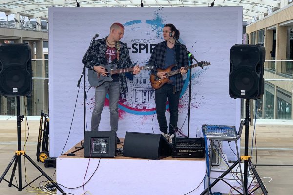 2 people playing guitar on a stage