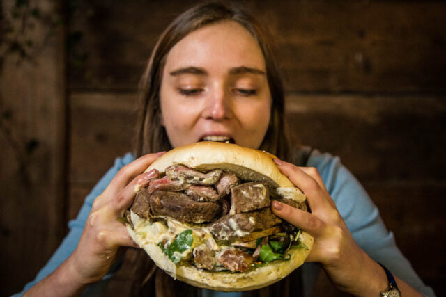 a girl eating a giant sandwich