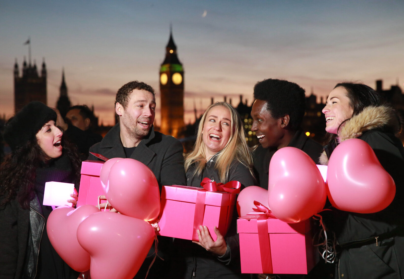 people holding pink gifts, london skyline