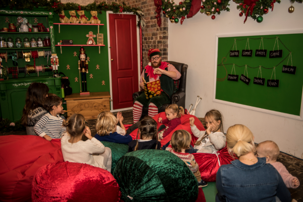 an elf reading a book to children