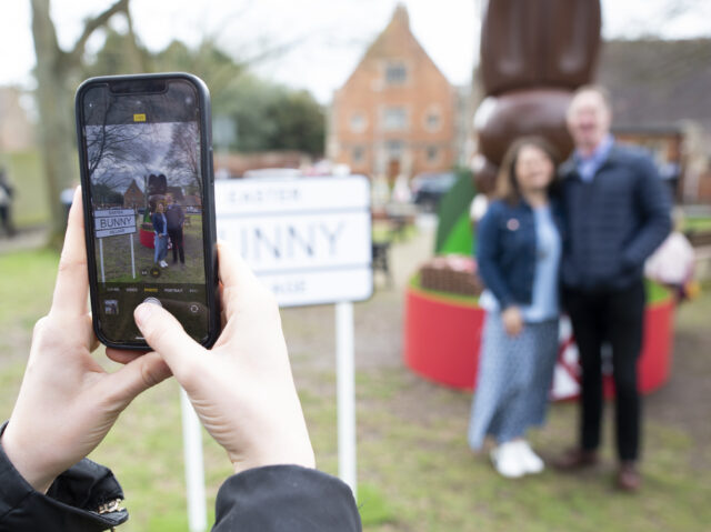 someone taking a photo in front of the giant chocolate bunny